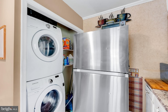 laundry room with stacked washer / dryer, wallpapered walls, and laundry area