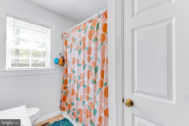 full bath with curtained shower, toilet, and baseboards