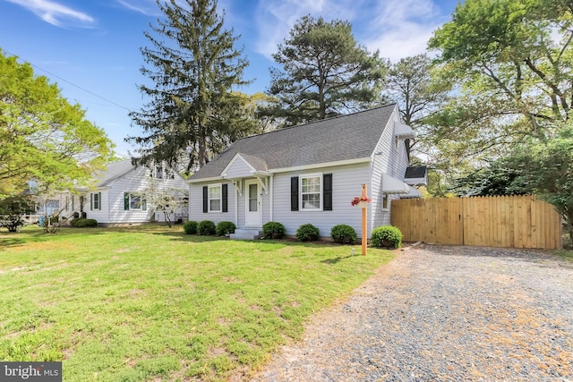view of front facade featuring fence, gravel driveway, a shingled roof, and a front yard