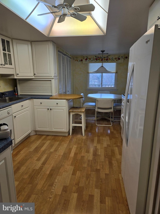 kitchen featuring white appliances, white cabinetry, a ceiling fan, and a sink