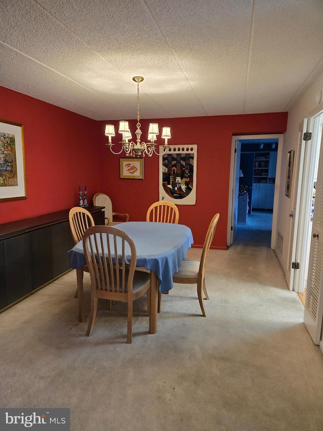 dining space featuring a textured ceiling, carpet, visible vents, and a chandelier