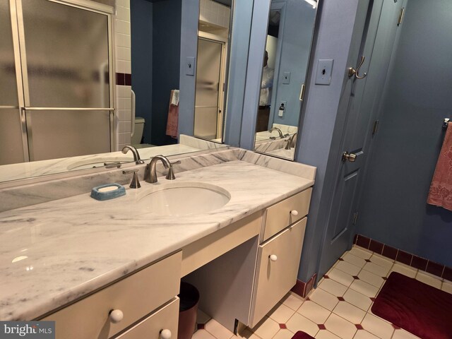 full bathroom with vanity, a shower stall, toilet, and baseboards