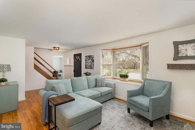 living area featuring stairway, baseboards, and light wood-style floors