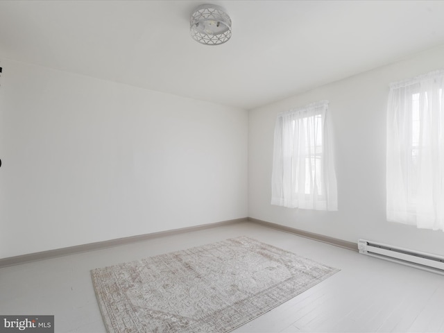 empty room with baseboards, baseboard heating, and wood finished floors