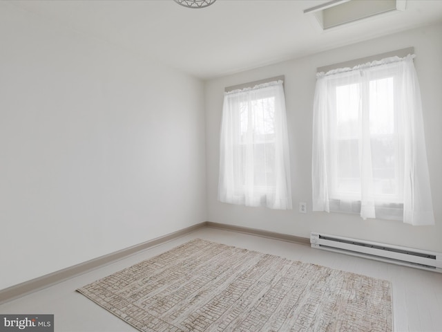 unfurnished room featuring a baseboard radiator and attic access