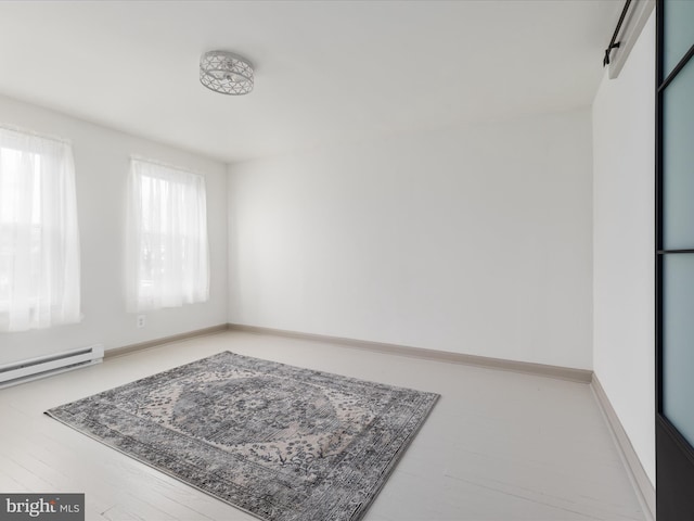 empty room featuring a baseboard heating unit and baseboards