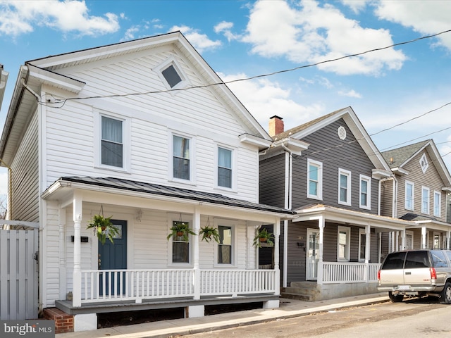 view of front facade featuring a porch, metal roof, a standing seam roof, and fence