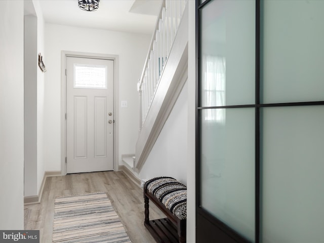 entryway with baseboards, stairs, and light wood-style floors