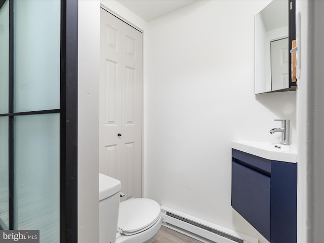 half bath featuring vanity, toilet, and a baseboard radiator