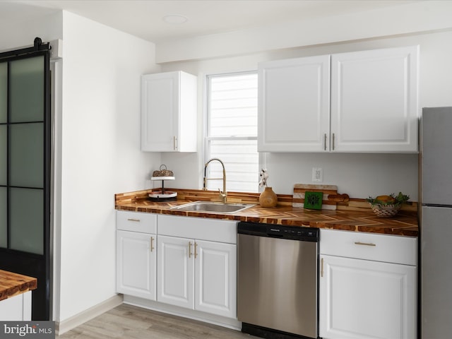 kitchen with wooden counters, appliances with stainless steel finishes, white cabinetry, and a sink