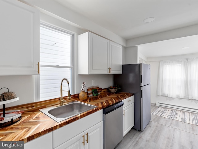 kitchen with butcher block counters, a baseboard heating unit, dishwasher, and a sink