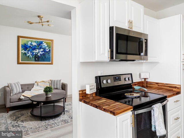 kitchen featuring white cabinetry, wood finished floors, appliances with stainless steel finishes, and wood counters