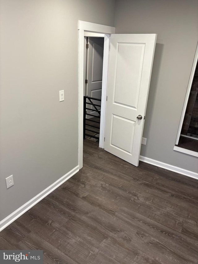 unfurnished bedroom with dark wood finished floors and baseboards