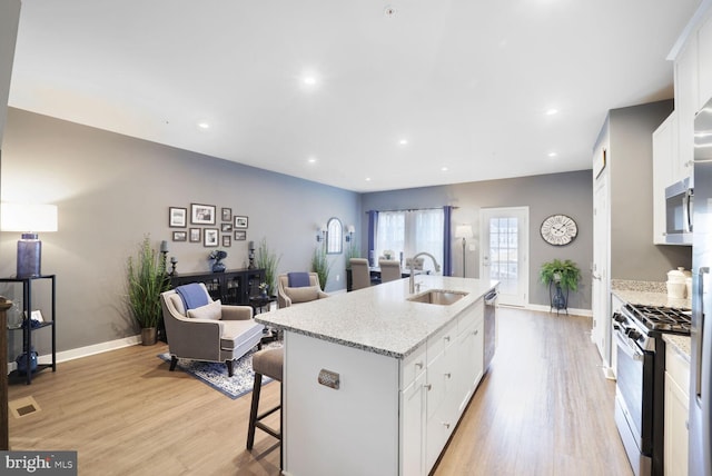 kitchen with white cabinets, light wood-type flooring, appliances with stainless steel finishes, and a sink