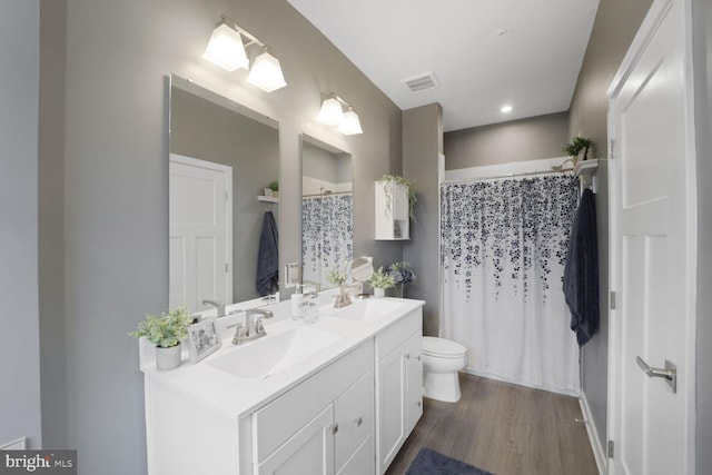 bathroom with visible vents, toilet, wood finished floors, and a sink