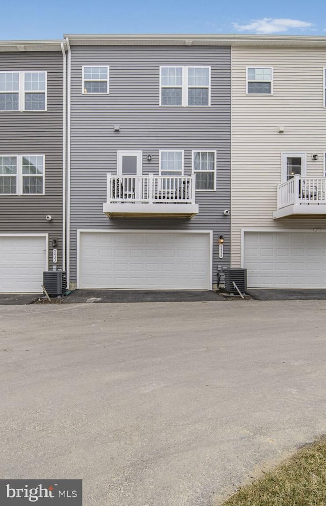 rear view of house with central air condition unit and an attached garage