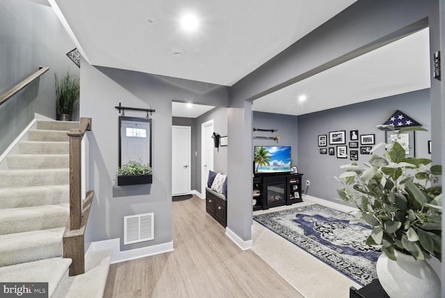 foyer entrance featuring stairway, wood finished floors, visible vents, baseboards, and a barn door