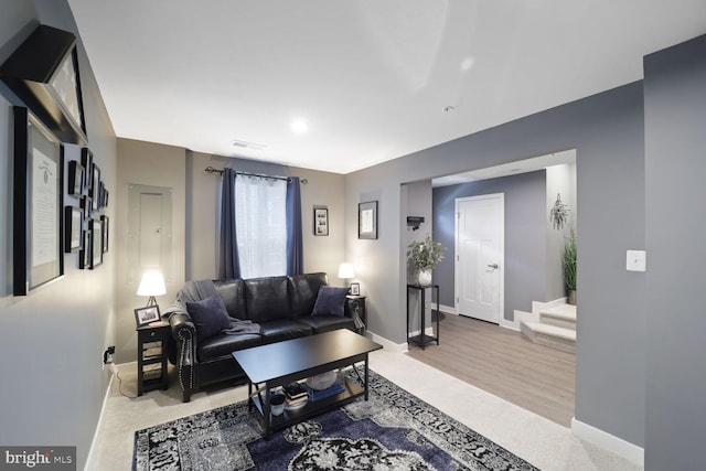 living area with visible vents, baseboards, and stairway