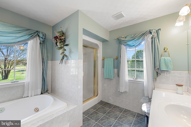 bathroom with a healthy amount of sunlight, vanity, visible vents, and tile walls