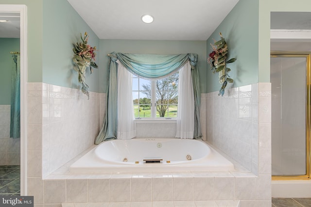 bathroom with a shower stall, a jetted tub, and a wainscoted wall
