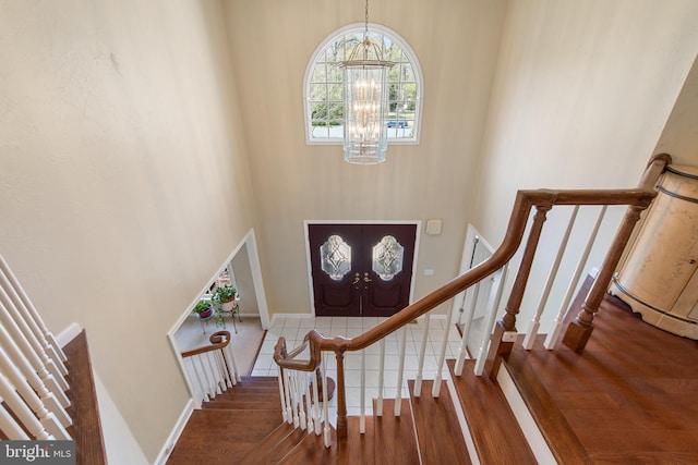 entryway with a chandelier, a high ceiling, baseboards, and wood finished floors