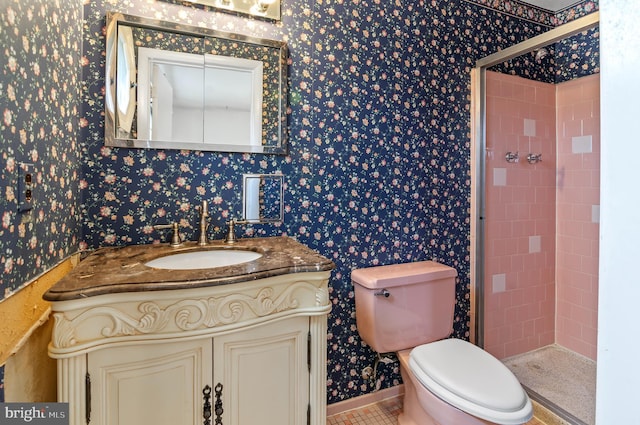 bathroom with toilet, a stall shower, wallpapered walls, baseboards, and vanity