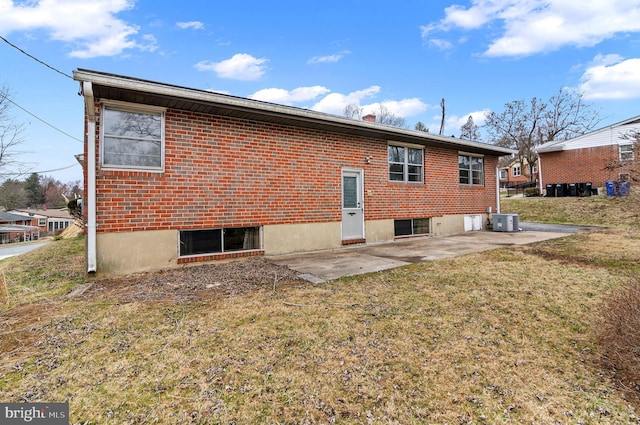 back of house featuring a patio, a lawn, central AC unit, and brick siding