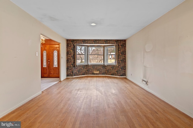 empty room featuring baseboards and light wood finished floors