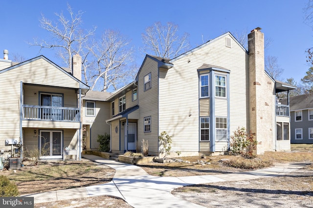 view of front of home with a balcony and a chimney