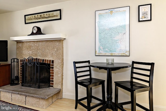 dining room with baseboards, a brick fireplace, and wood finished floors