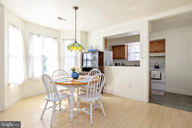 dining space featuring light wood-style flooring, visible vents, and a wealth of natural light