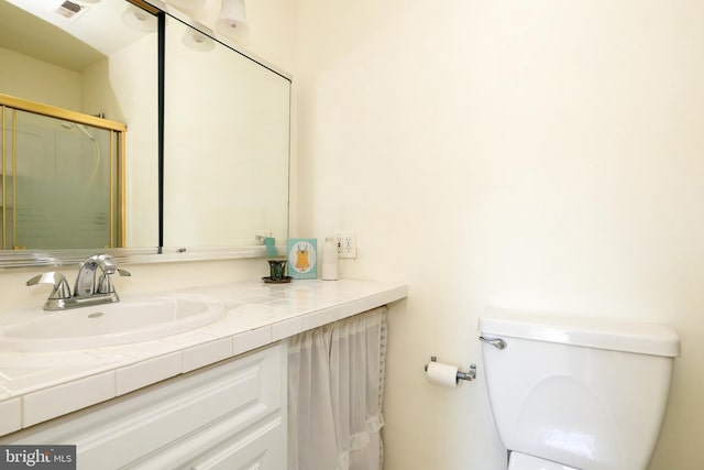 bathroom with a shower with shower door, visible vents, toilet, and vanity