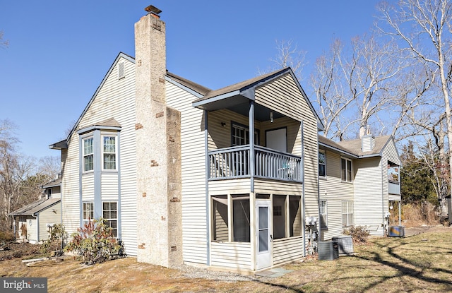 view of side of property with central AC, a chimney, a balcony, and a sunroom