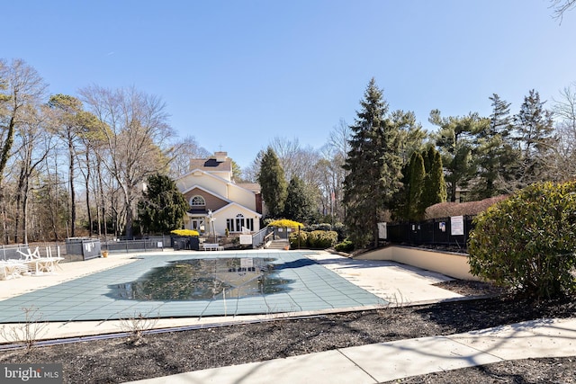 community pool with a patio and fence