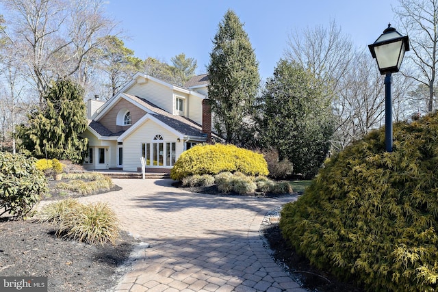 view of front of property featuring a chimney and decorative driveway