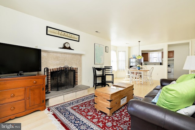 living room with light wood-type flooring and a fireplace with raised hearth