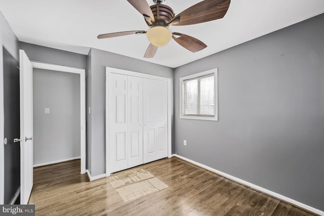 unfurnished bedroom featuring a closet, ceiling fan, baseboards, and wood finished floors