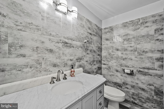 bathroom with vanity, toilet, and tile walls