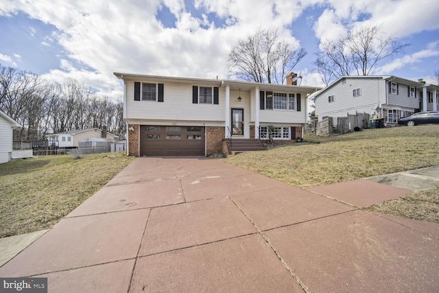 raised ranch with fence, driveway, an attached garage, a front lawn, and brick siding