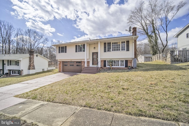 split foyer home with a garage, driveway, brick siding, and a front yard