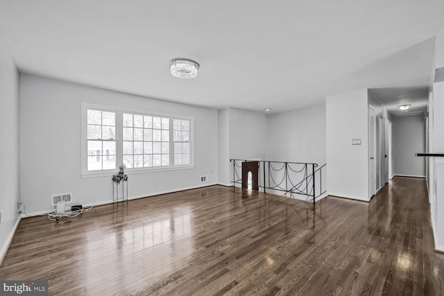 unfurnished room with wood finished floors, visible vents, and baseboards