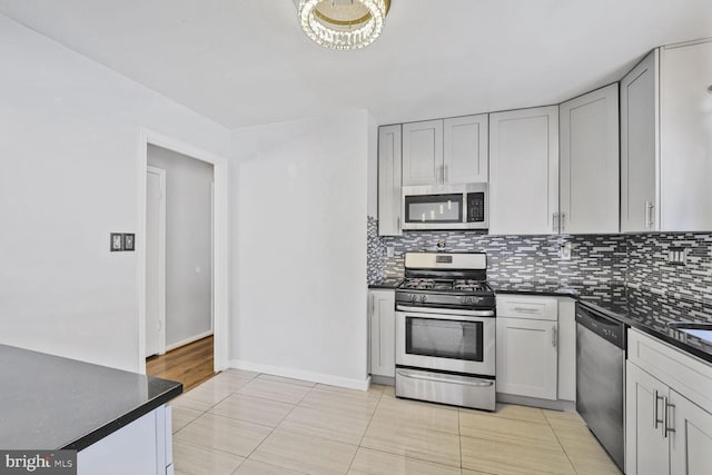 kitchen featuring backsplash, stainless steel appliances, baseboards, and dark countertops