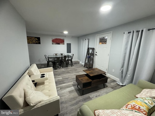 living room featuring electric panel, baseboards, wood finished floors, and recessed lighting