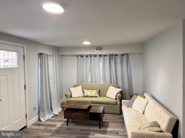 living area with visible vents, baseboards, and wood finished floors