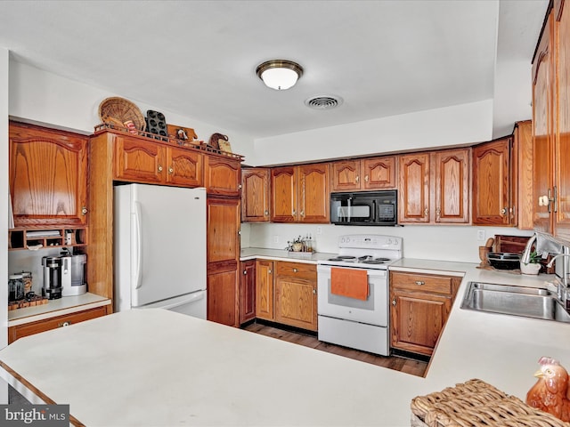 kitchen featuring brown cabinetry, white appliances, light countertops, and a sink