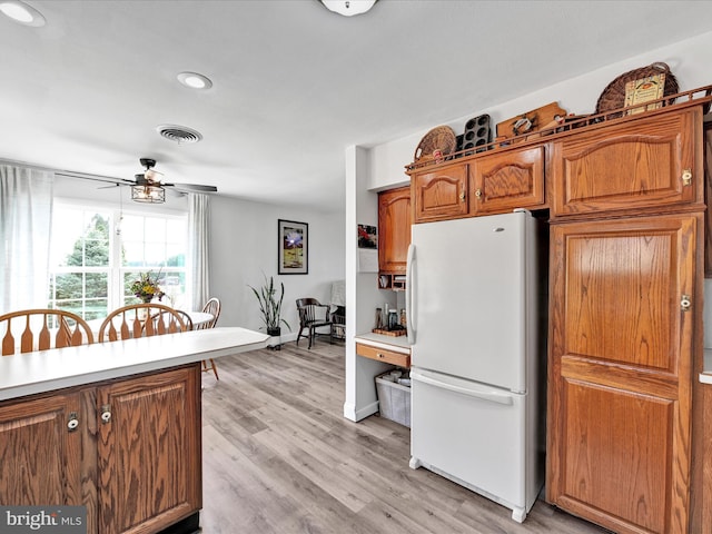 kitchen with visible vents, light wood-type flooring, brown cabinets, freestanding refrigerator, and a ceiling fan