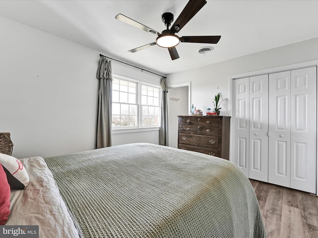 bedroom with visible vents, a closet, wood finished floors, and a ceiling fan