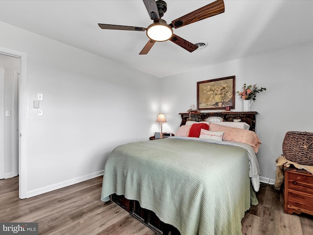 bedroom with ceiling fan, wood finished floors, visible vents, and baseboards