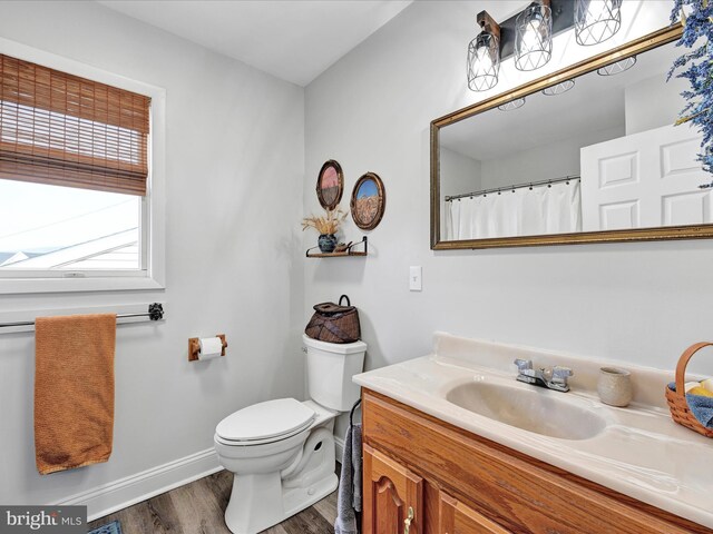 bathroom featuring toilet, vanity, baseboards, and wood finished floors