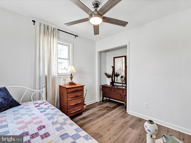 bedroom featuring baseboards, wood finished floors, and a ceiling fan